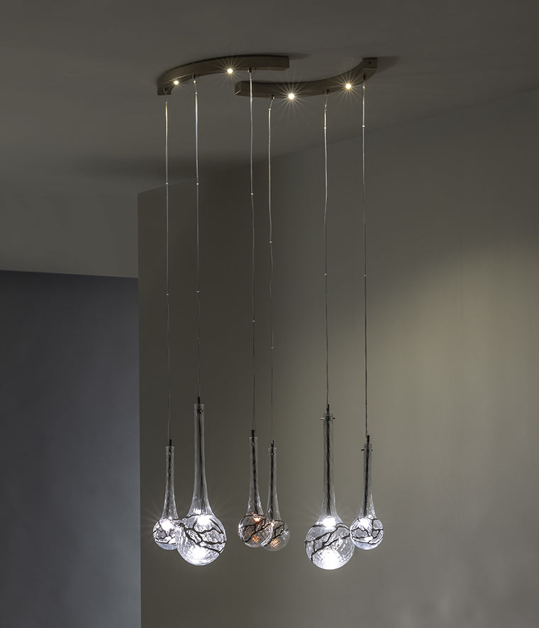 Lampada a sospensione modulabile su base ad arco in vetro soffiato e inserti metallici