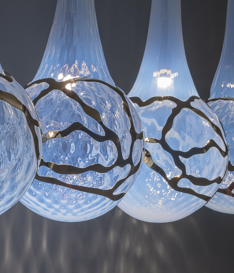 Lampada a sospensione modulabile su base ad arco in vetro soffiato e inserti metallici